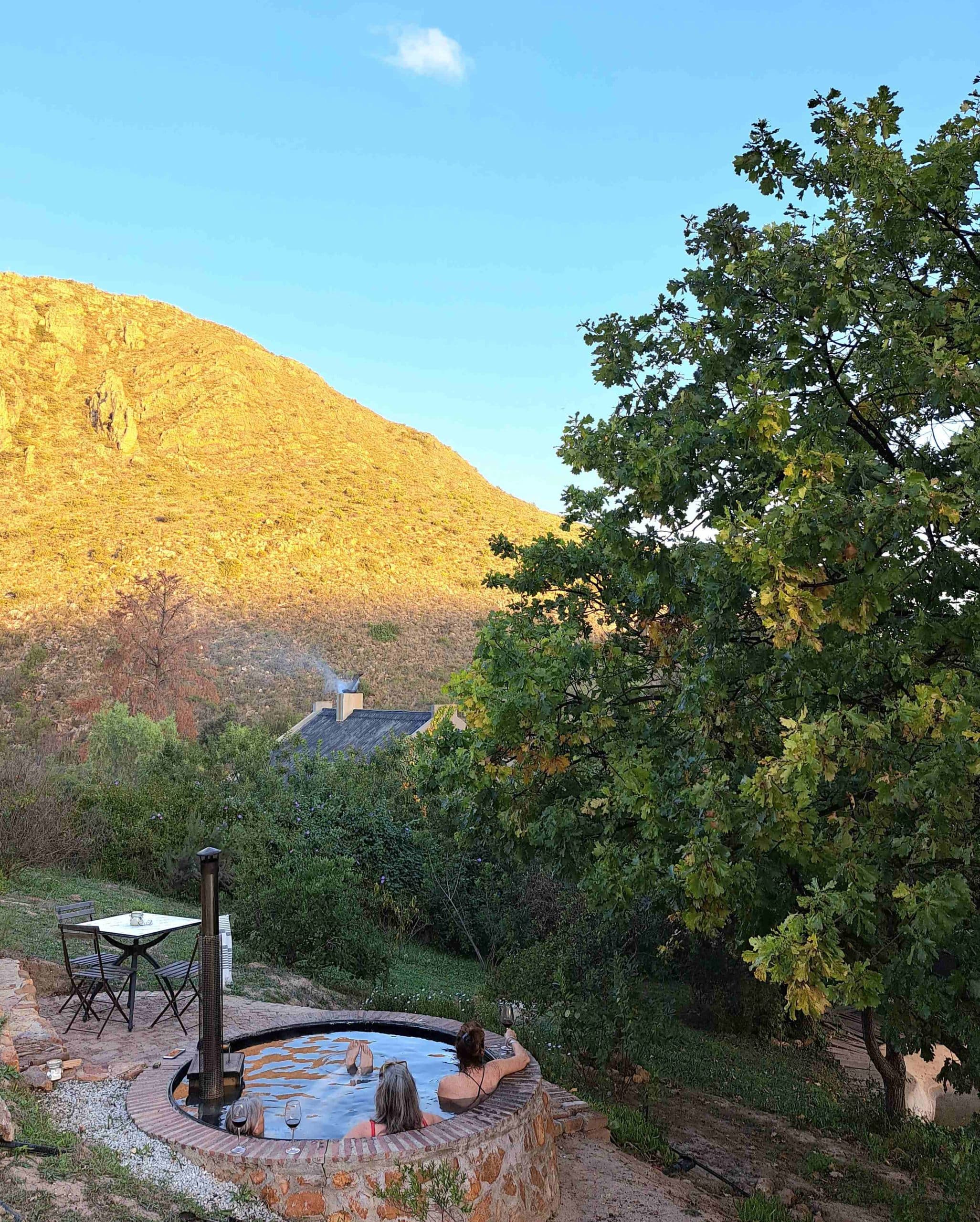 The Farmhouse at Porcupine Hills: Two people in hot tub below golden sunlit hillside