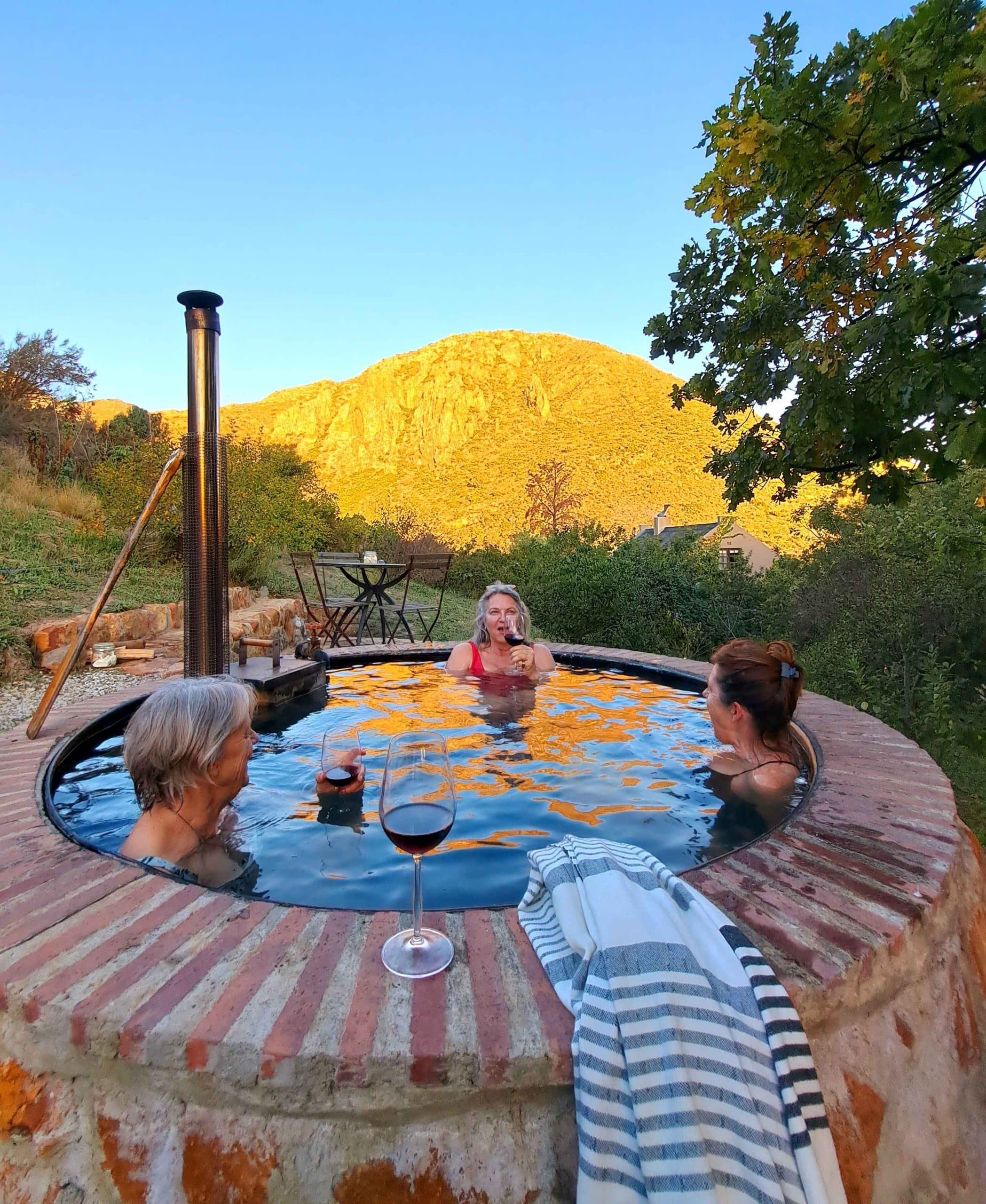The Farmhouse at Porcupine Hills: Three people in steamy wood-fired tub, wine, golden mountain at dusk