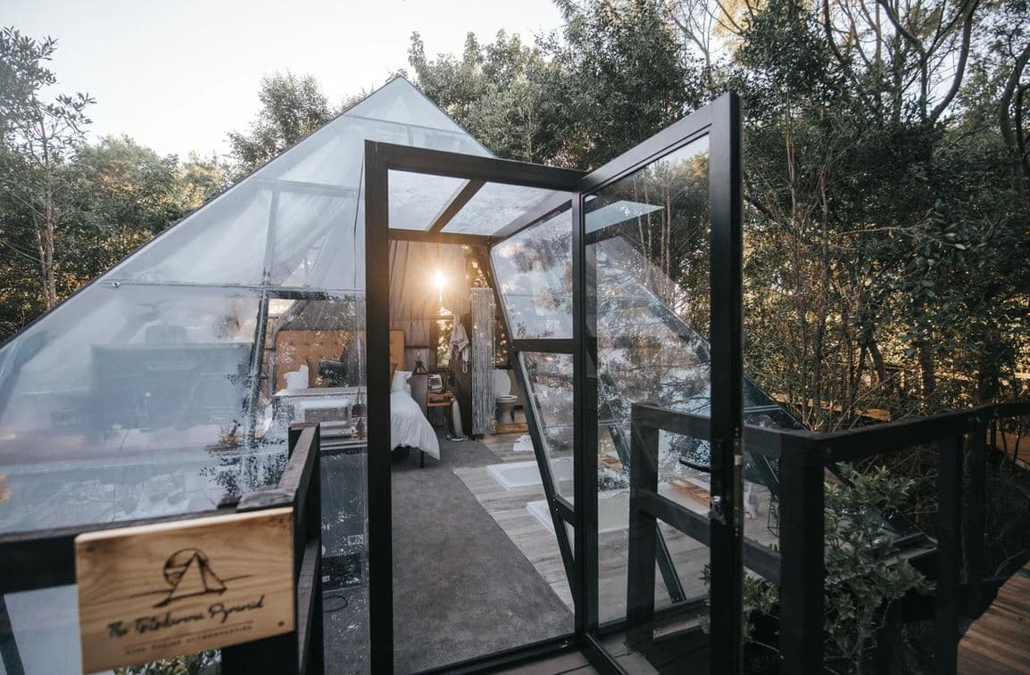 The Pyramid at Misty Mountain Reserve: Glass pyramid with open door, warm glow inside, in trees