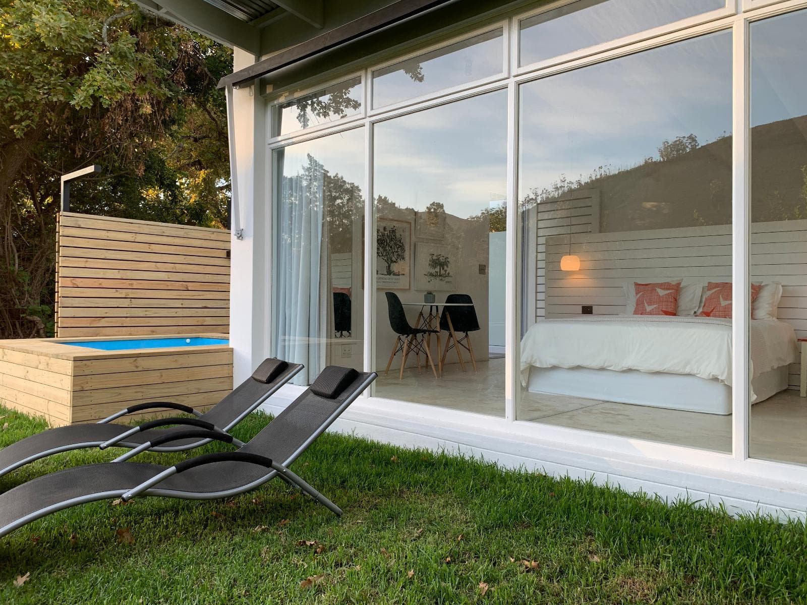 Gite Studio Franschhoek: Loungers on lawn, plunge pool and cabin with dusk glass facade