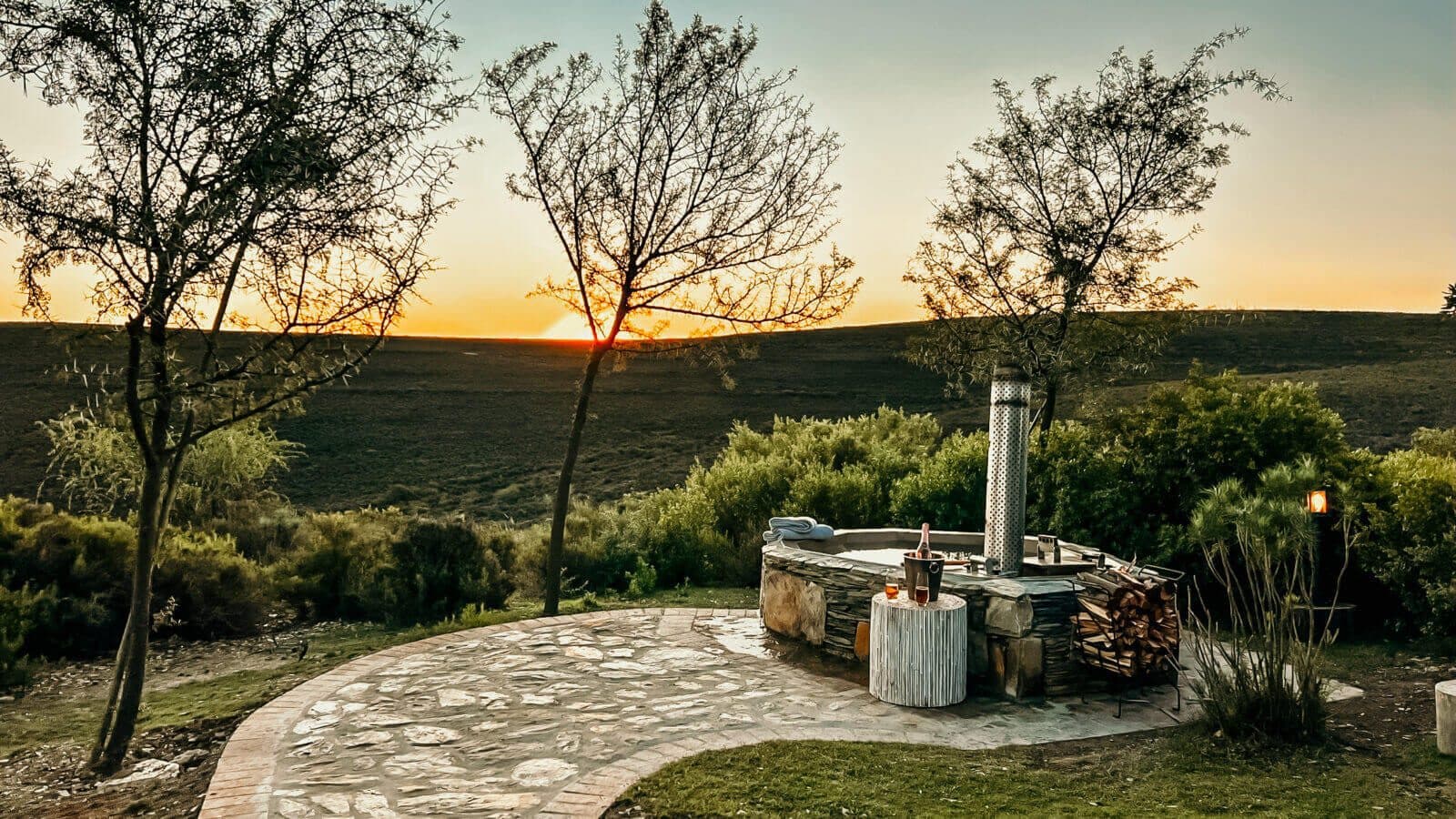 Melozhori Cottage: Stone wood-fired hot tub with firewood, sunset over Karoo hills