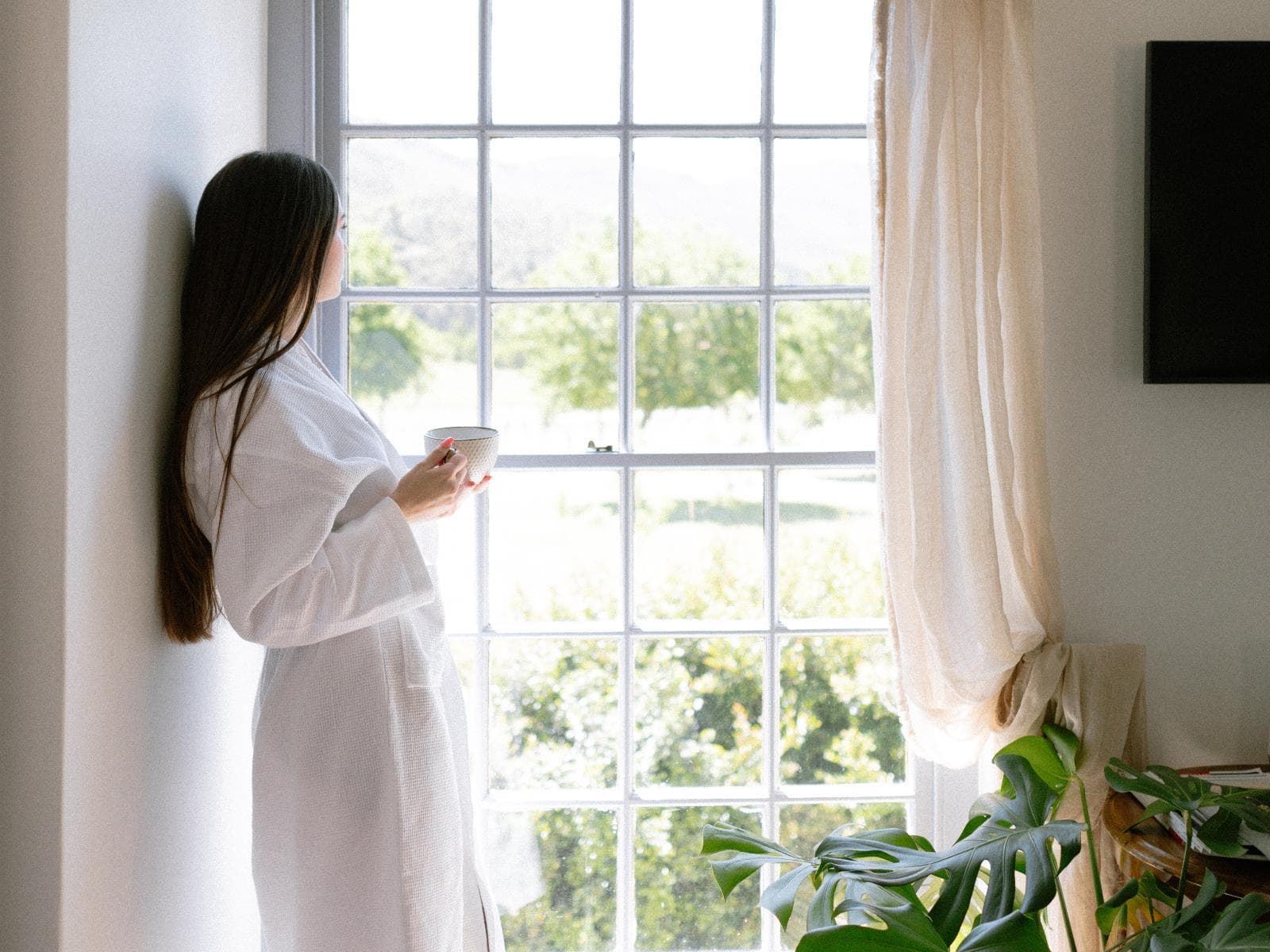 Luxury Family Suite: a woman in a robe with coffee, gazing out over the garden